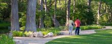 Two people stroll along a wooded pathway.